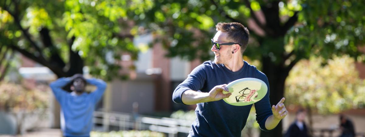Man playing frisbee outside on CWRU campus