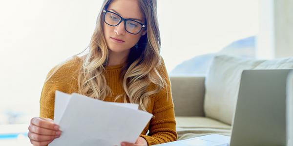 Student holding print outs next to a computer