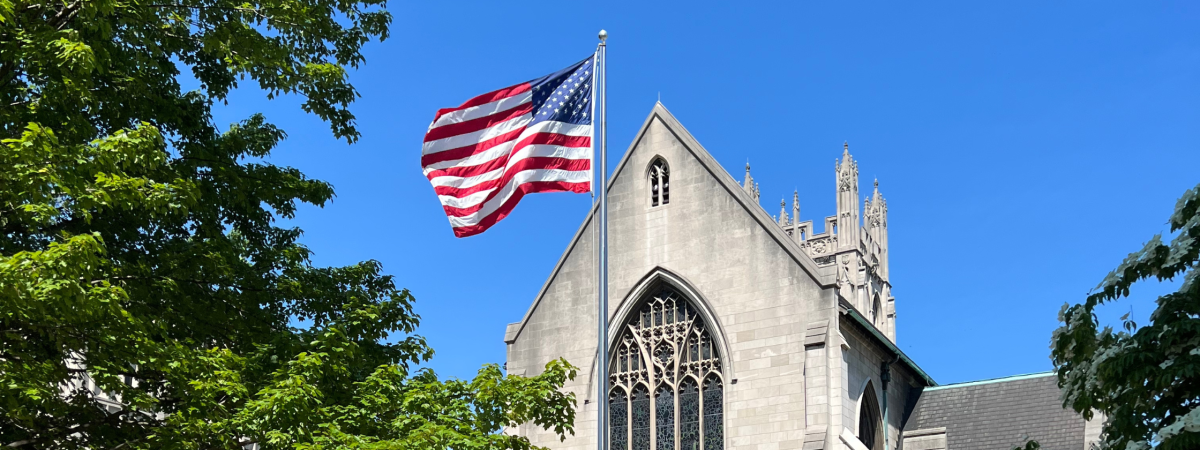 American flag on a flag pole waving in front of Amasa Stone Chapel
