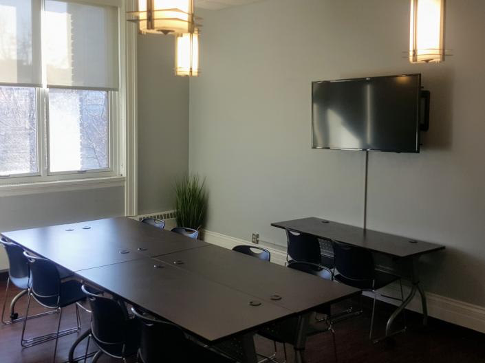 An empty view of Meeting Room 206 with its table and chairs and a television.