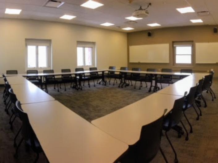Empty photo of Room 302, with tables set up in a rectangle and chairs around them.
