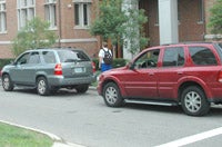Two cars parallel parked outside a red brick building