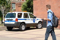 Student walking past a security vehicle parked near a red brick building