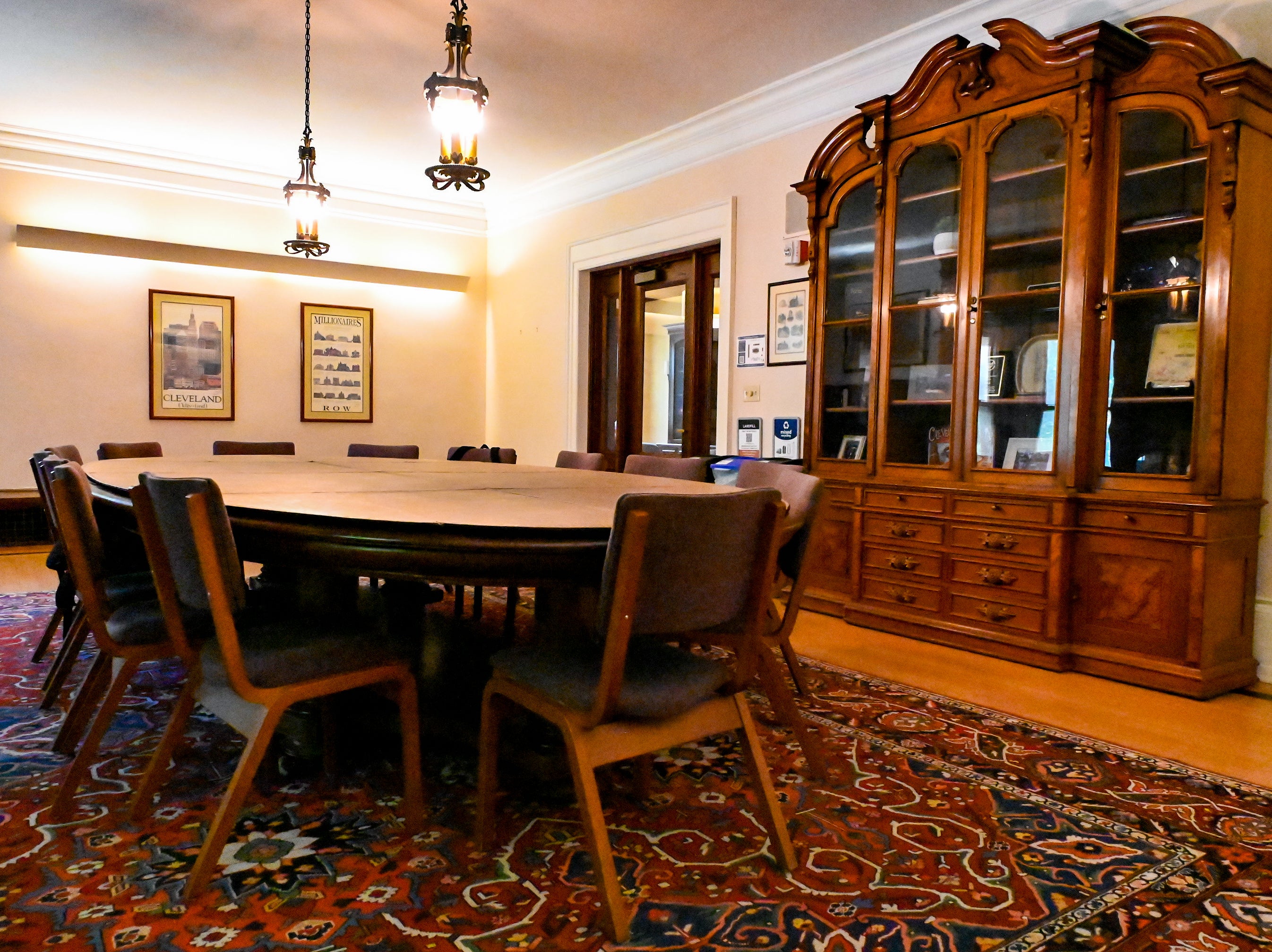 Photo of the Cleveland Room in Thwing Center with a large confrence table on the left and an antique bookcase on the right