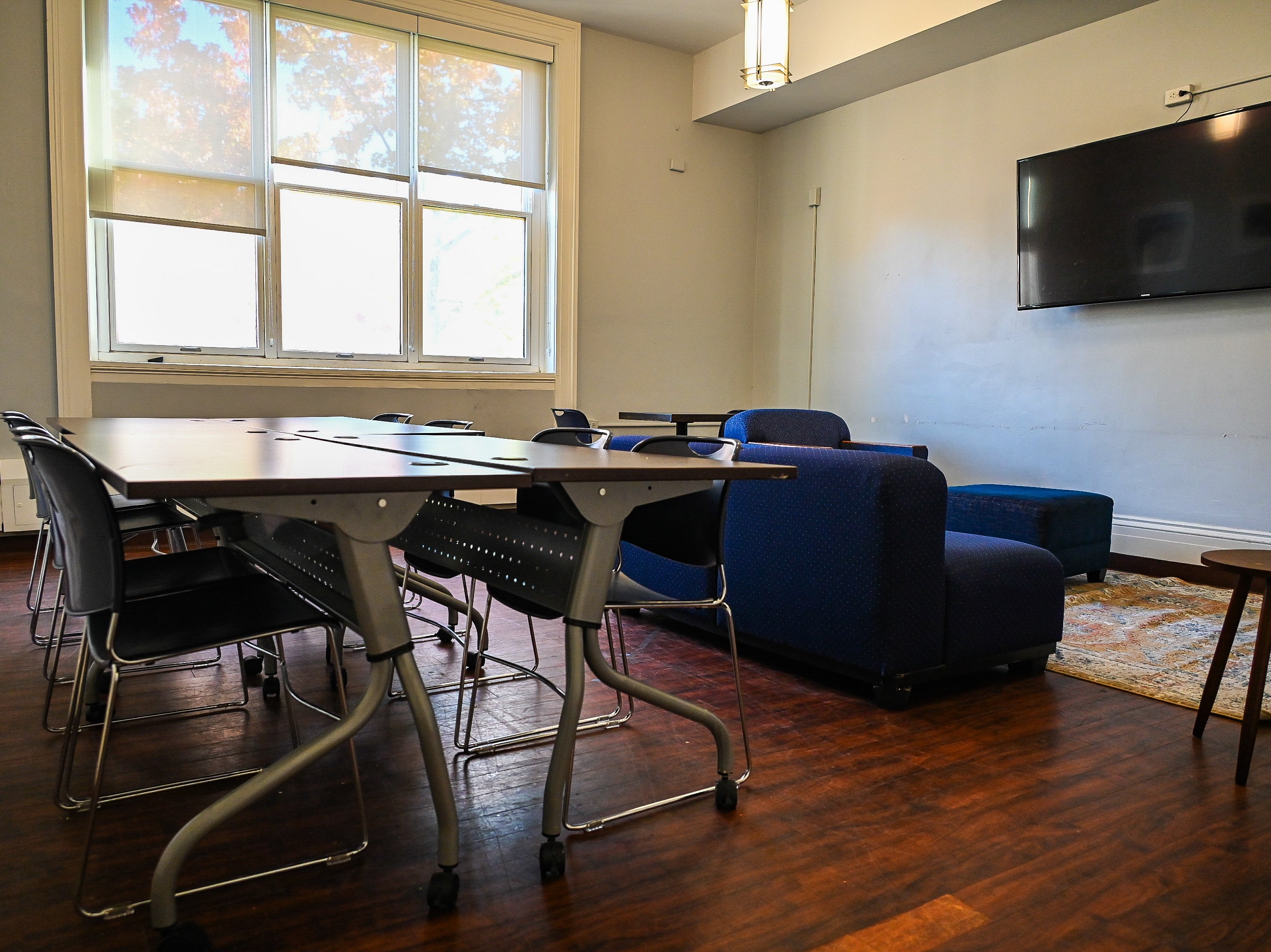 Empty Room 218 in Thwing Center with table and chairs and couches facing the TV on the right wall