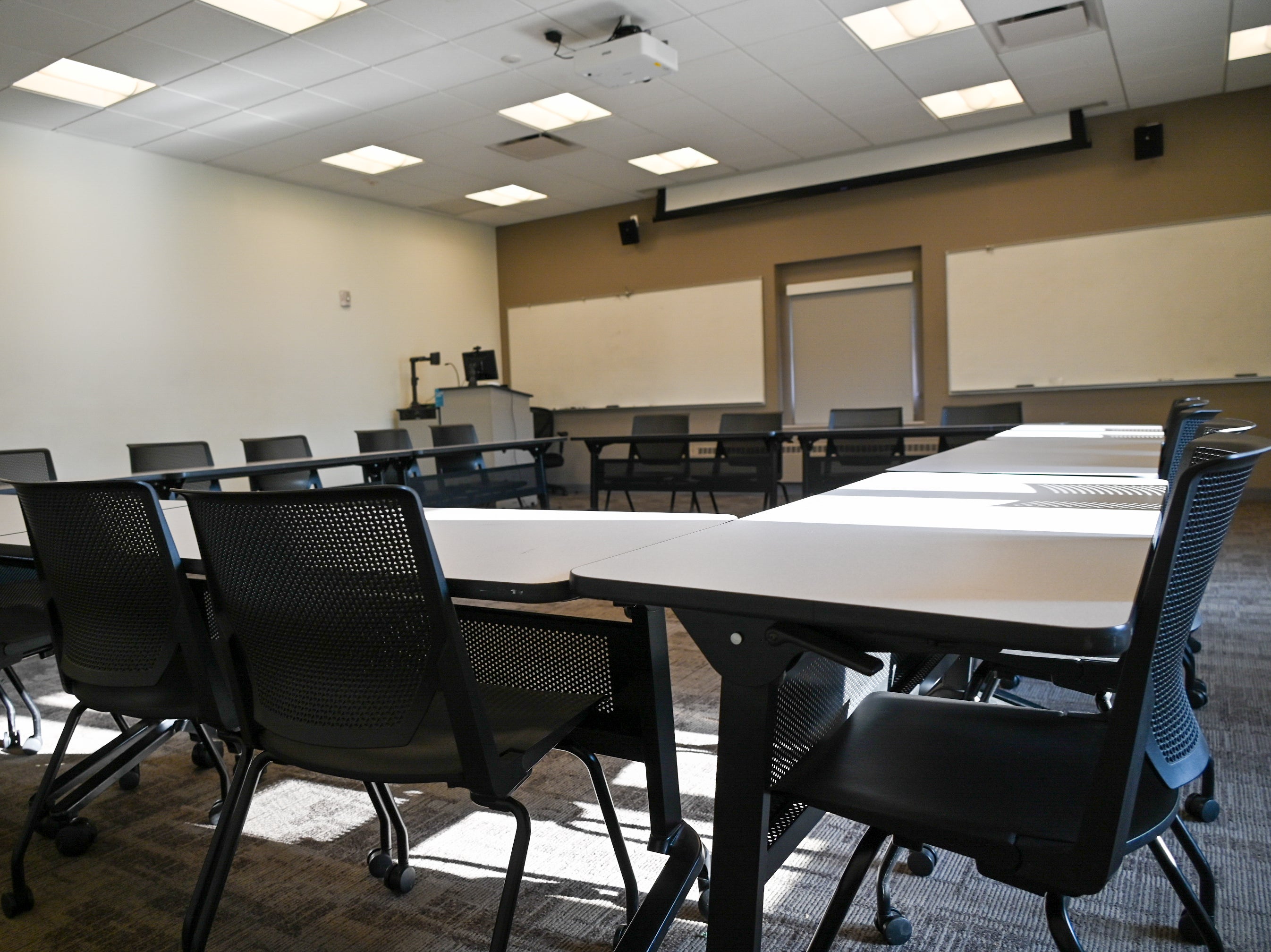 Empty Room 301 in Thwing Center with classroom tables and chairs facing towards lecture in front of room