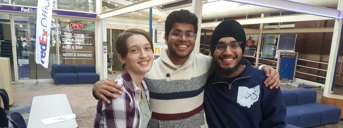 Three students standing together in the Thwing Atrium