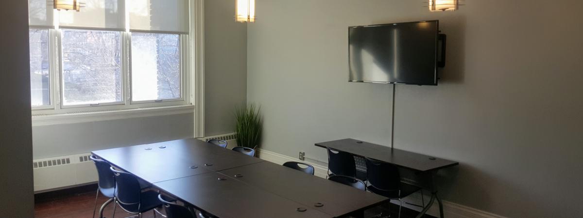 An empty view of Meeting Room 206 with its table and chairs and a television.