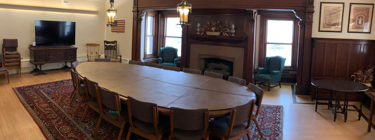 An empty view of the Cleveland Room with its large round conference table and a television.