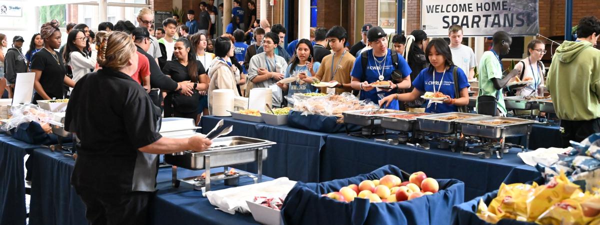 Students lined up getting served food at multiple buffet lines