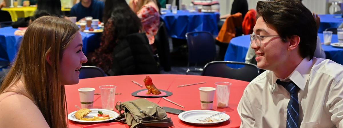 Two students facing and talking to eachother during an event