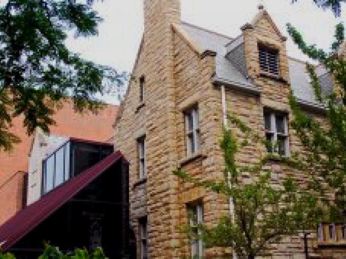 Close up view of the exterior of Eldred Hall where the classic front meets the modern atrium with some tree branches in frame on either side