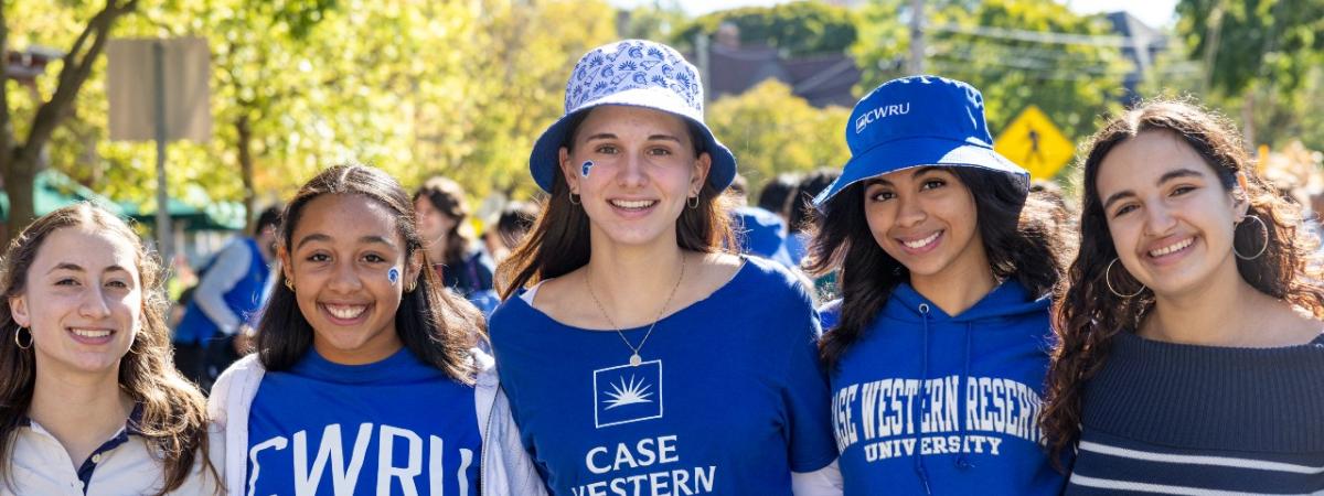 Five students wearing CWRU shirts and hats smile together for a photo.