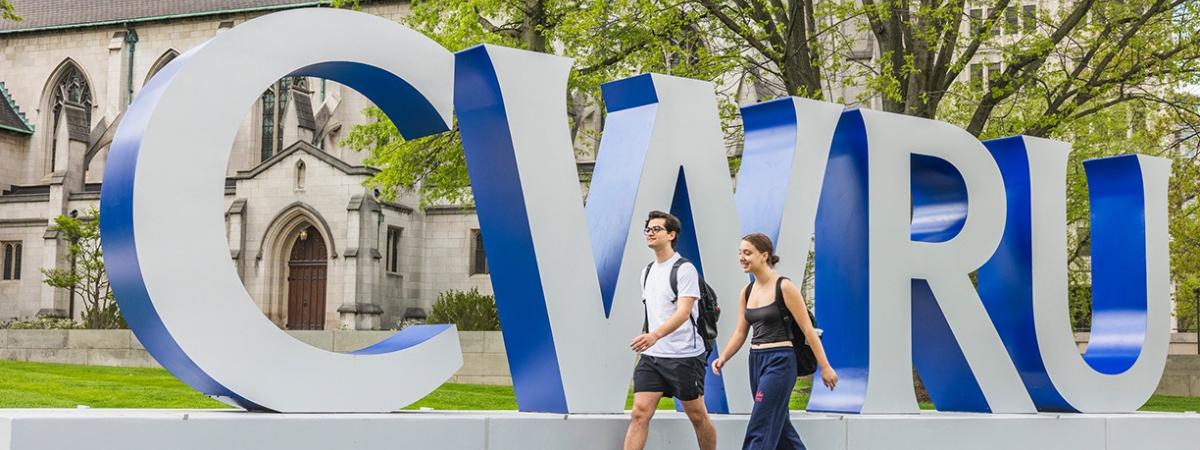 Students walking by CWRU letter sign on campus