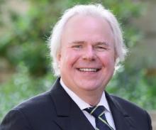 James Galm wears a suit and smiles for a photo.