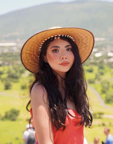young woman in front of landscape with wide brimmed hat