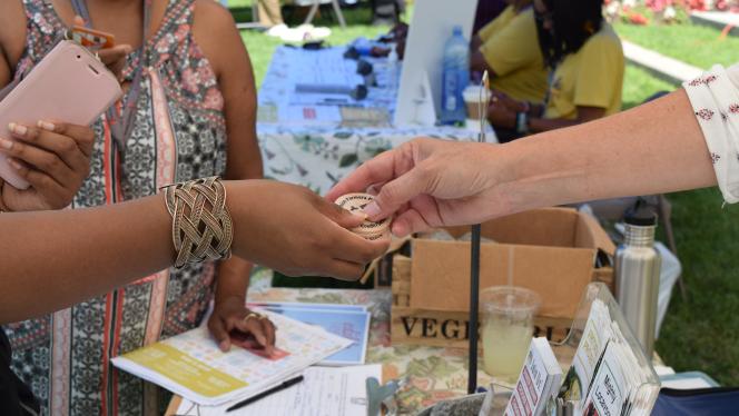 Two people exchange tokens at a farmers market