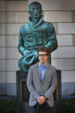A photo of Dave Lucas standing in front of a statue of poet Hart Crane