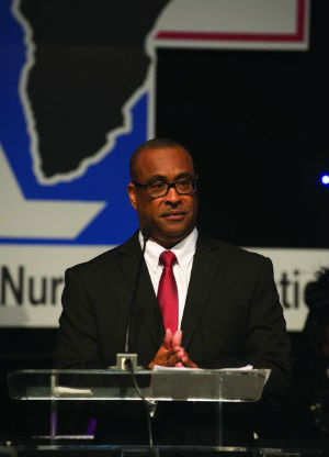 A photo of Eric Williams standing at a podium