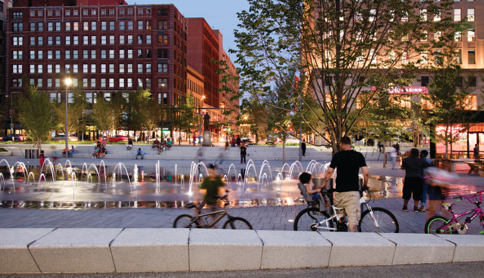 Public Square water fountain at night with children on bicycles