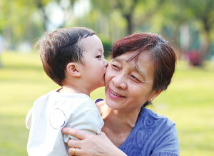 A young toddler kissing the cheek of an older woman