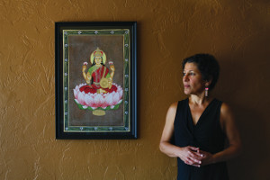 A photo of CWRU social work faculty Deborah Jacobson standing next to a painting of a religious icon sitting on a pink flower