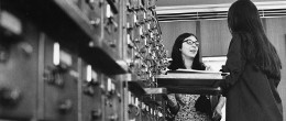 A black and white photo of two female students at the library card catalogue.