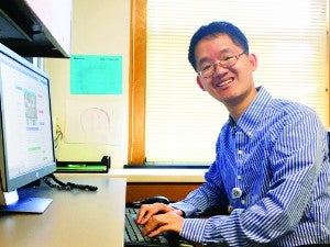 Male student sitting at a desk and typing on a computer keyboard