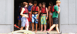Photo of kids at camp with swimming suits and vests standing in a doorway.