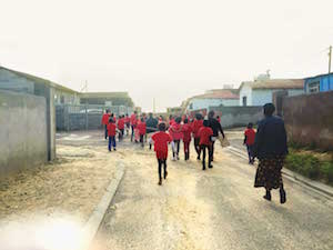 Women and children walking down a dirt street in South Africa.