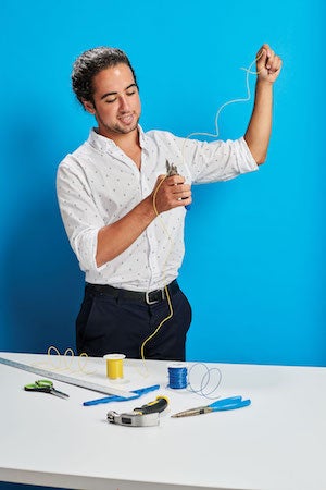 Case Western Reserve University student Matt Campagna of Reflexion Interactive Technologies cutting wire with a blue background.