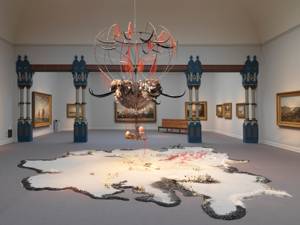 An art sculpture by Rina Banerjee displayed, with components hanging from the ceiling