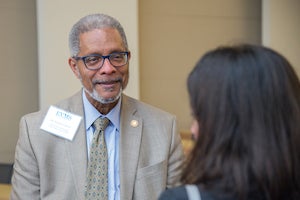 Virginia's health commissioner Norman Oliver seated and listening to a person