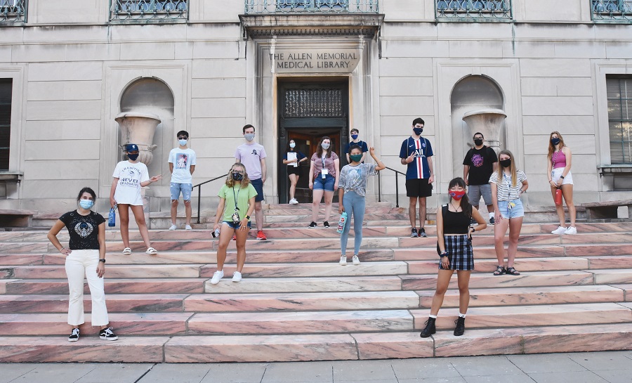 14 students stand on the steps of the Allen Memorial Medical Library.