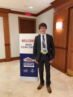 Photo of Nathan Lesch in front of a presidential debate welcome sign