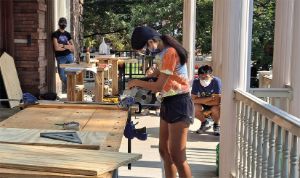 A student wearing a mask and safety glasses using a circular saw.