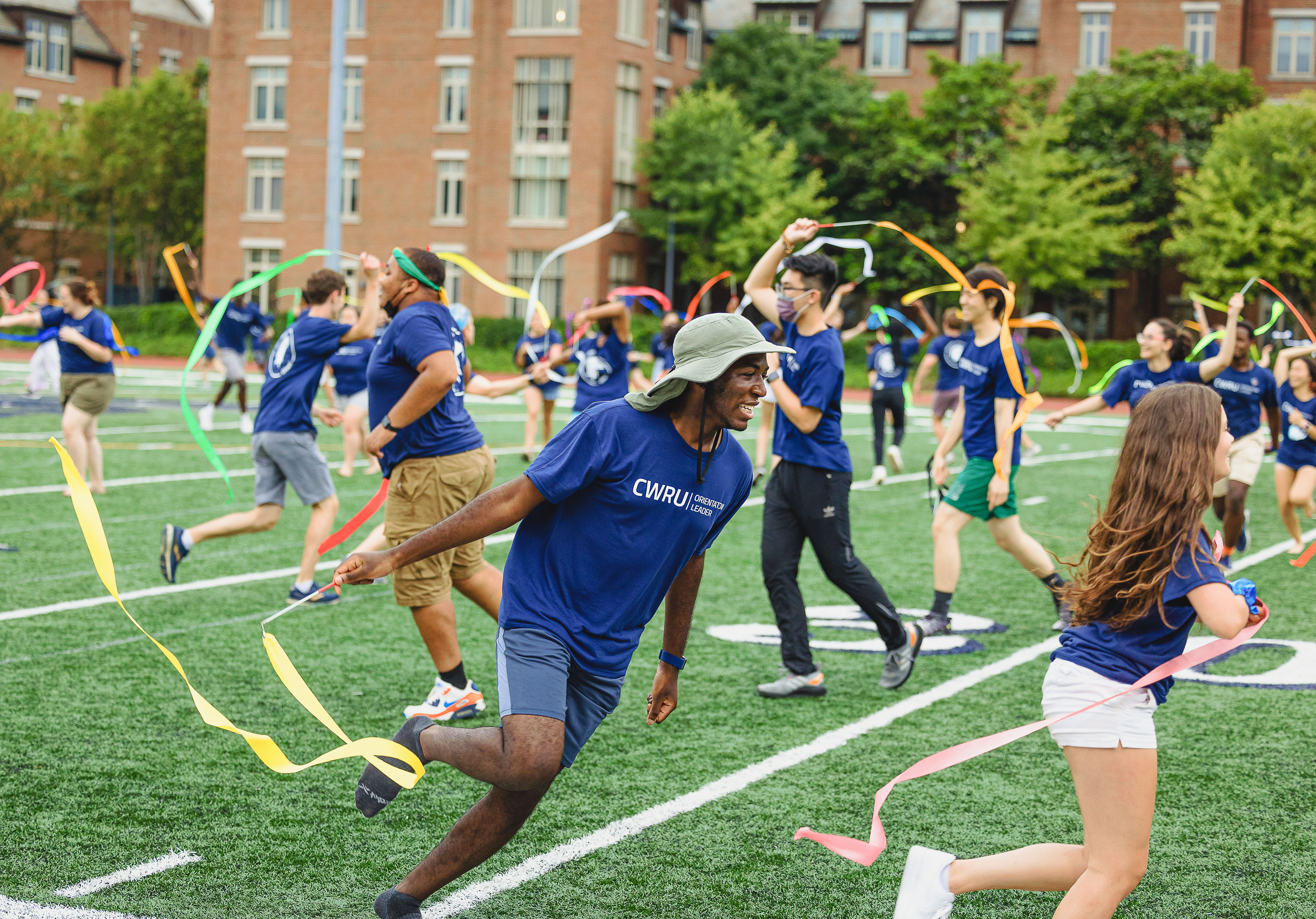 CWRU students run around on a football field with ribbon wands.
