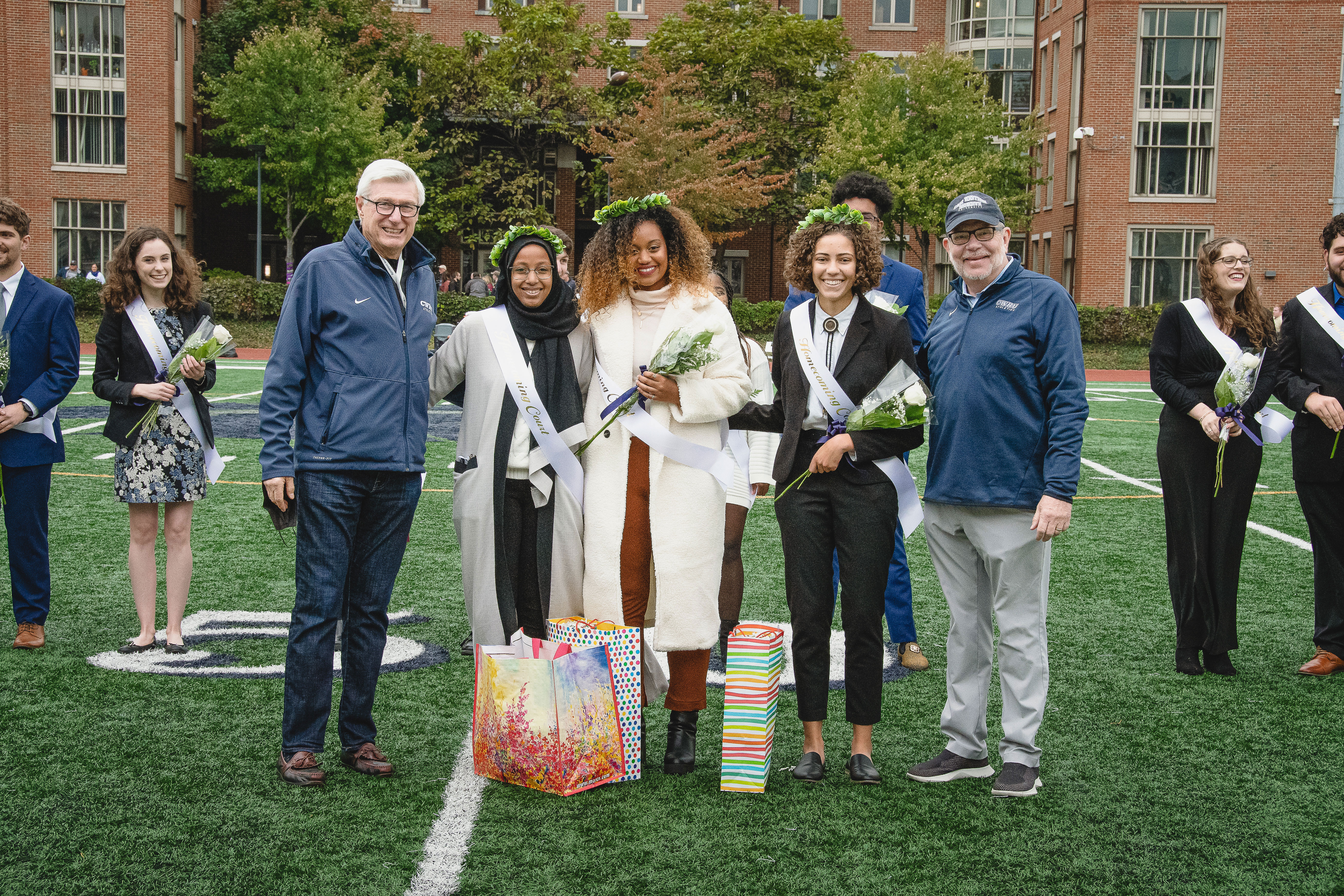 Lou Stark and Eric Kaler stand on either side of members of the student
    homecoming court (Yageen Queen Hassan, Wintana Eyob and Camille Witt) 