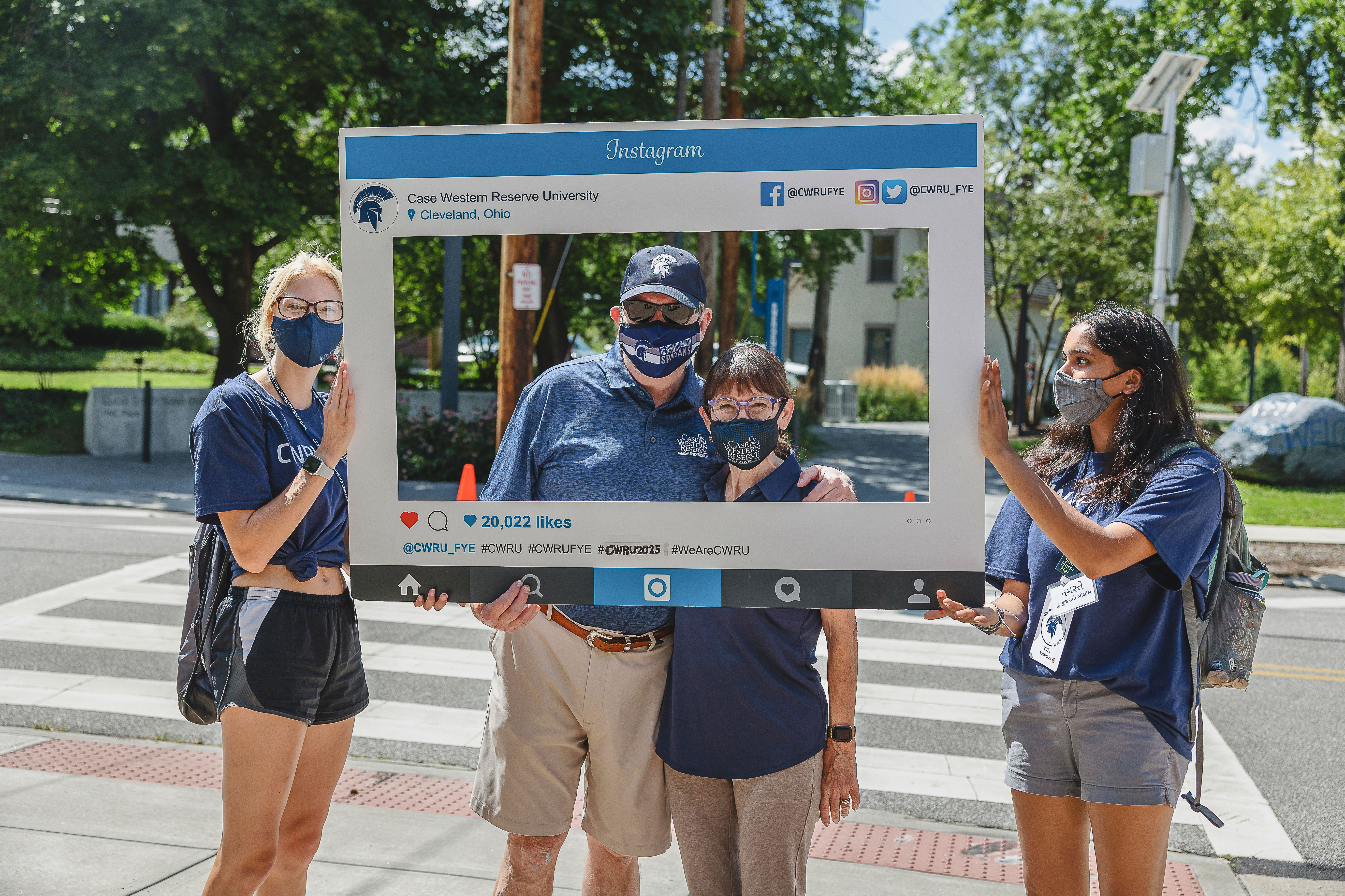 Four people wearing masks and holding an Instagram cardboard cutout