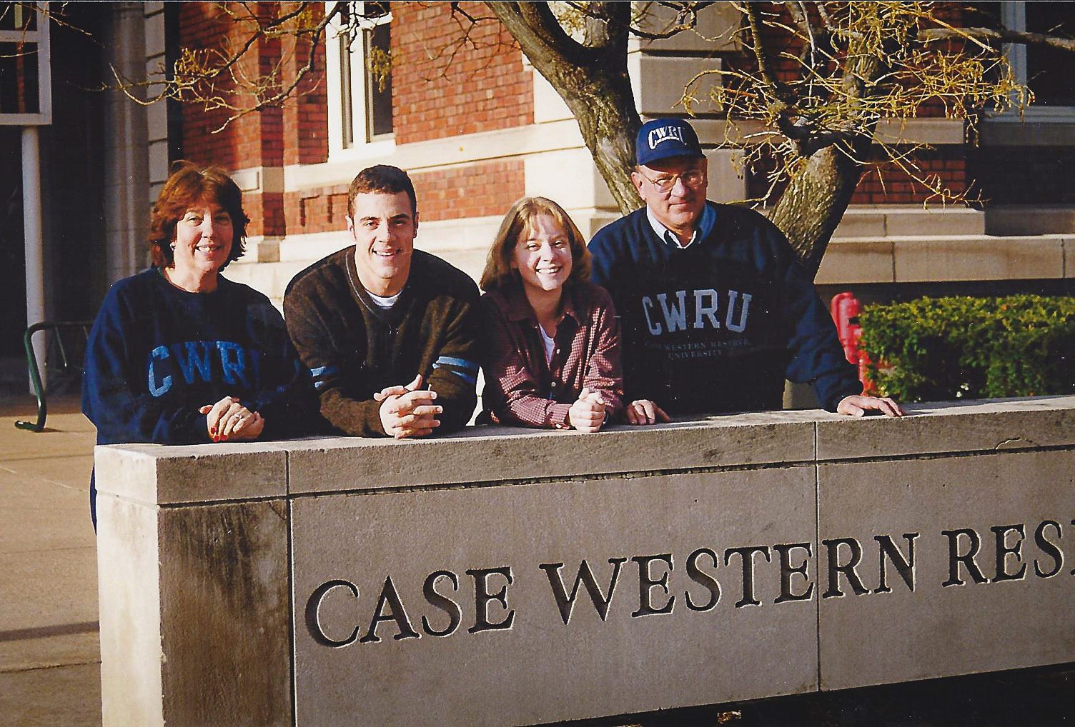 Image of John Kobs standing with his sister and parents behind a CWRU sign