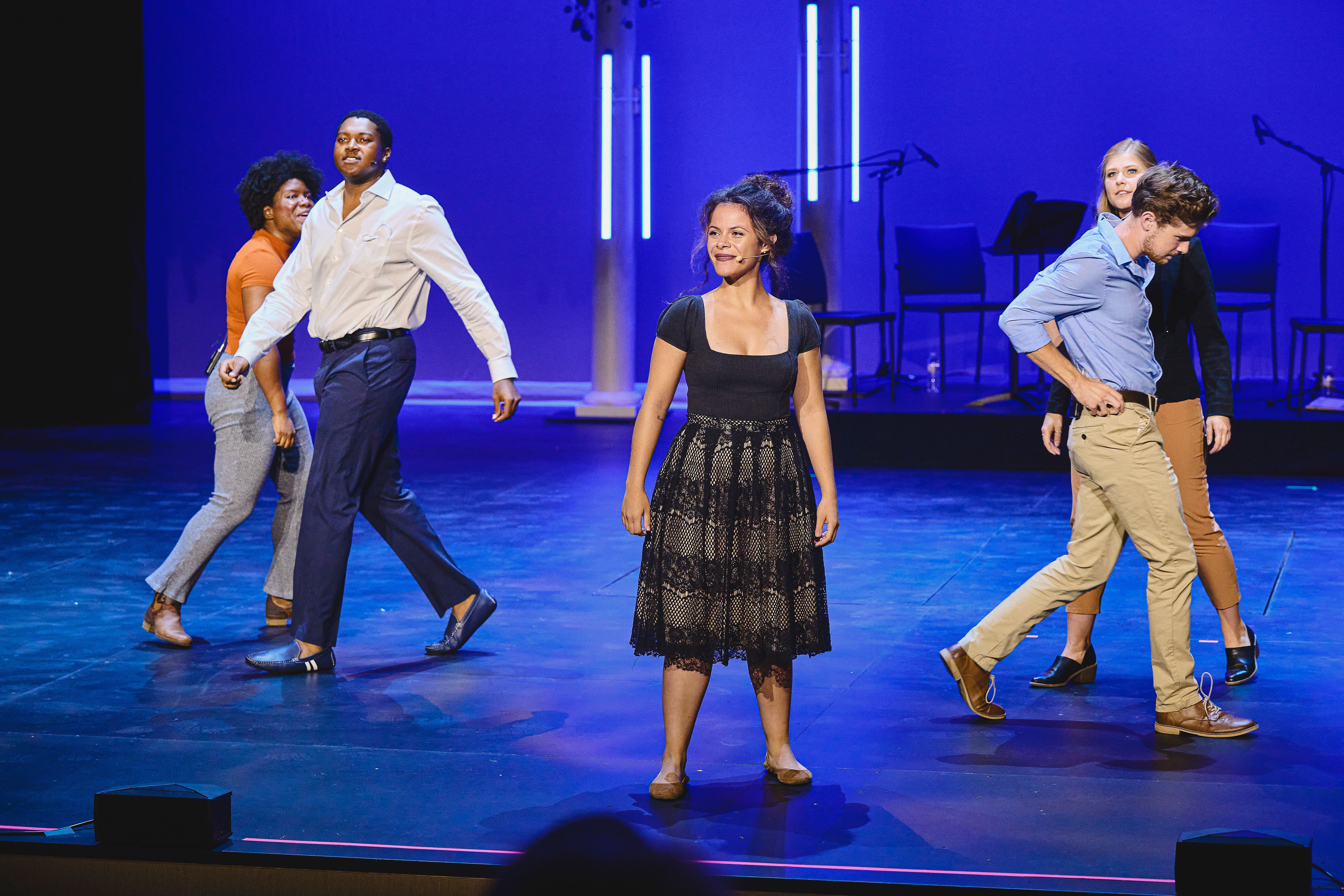 Five students performing on a stage