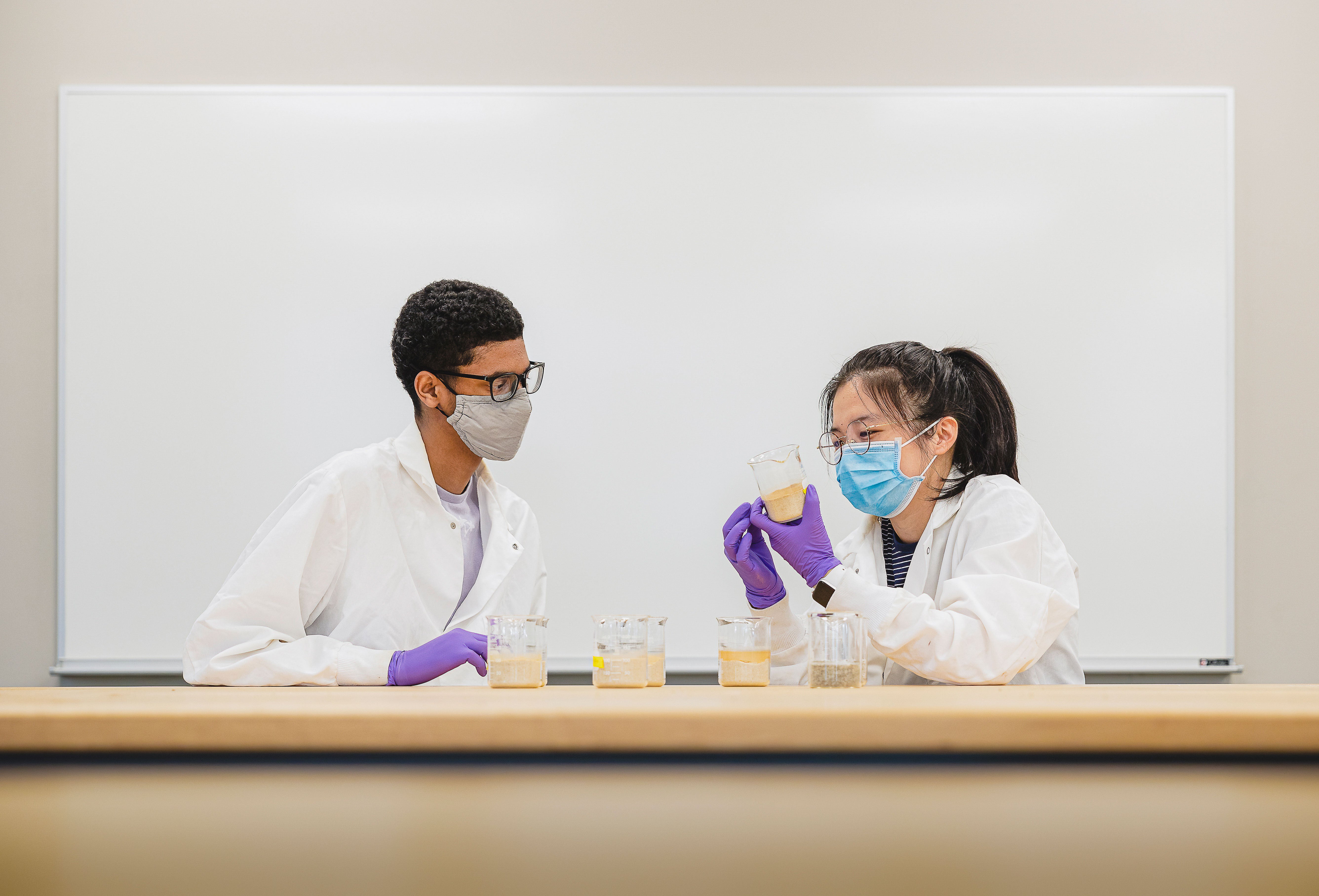 Brahaan Singh and Xijin Zhang sit examining beakers together