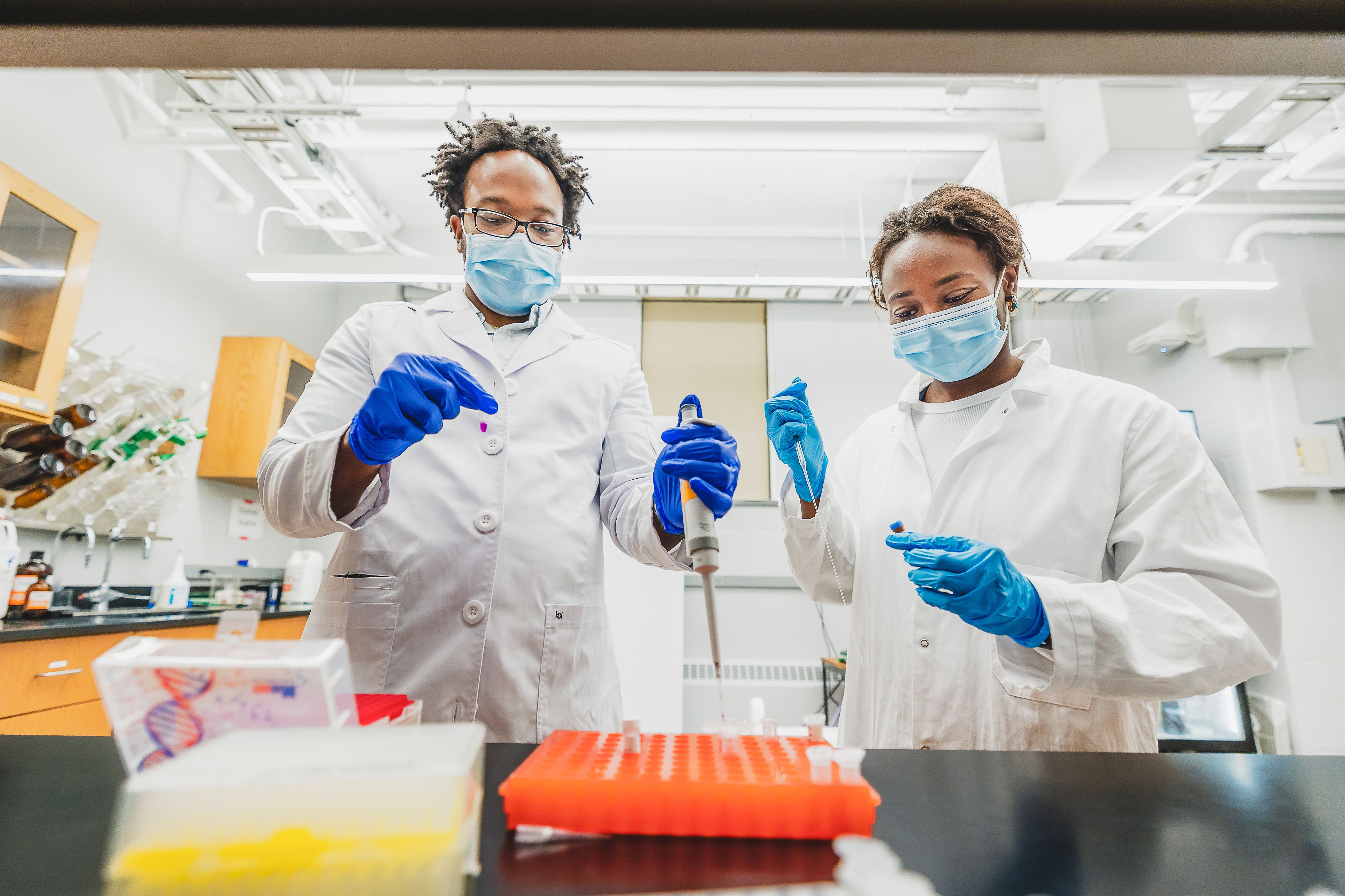 Barrington Henry and Linzy Malcolm experiment in a lab together holding test tubes