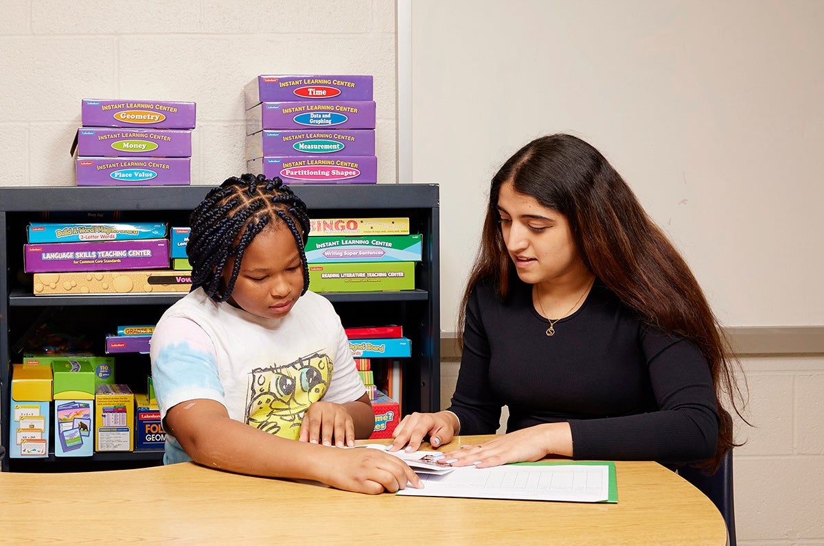 A Case Western Reserve student reads at a table with an elementary-school student.