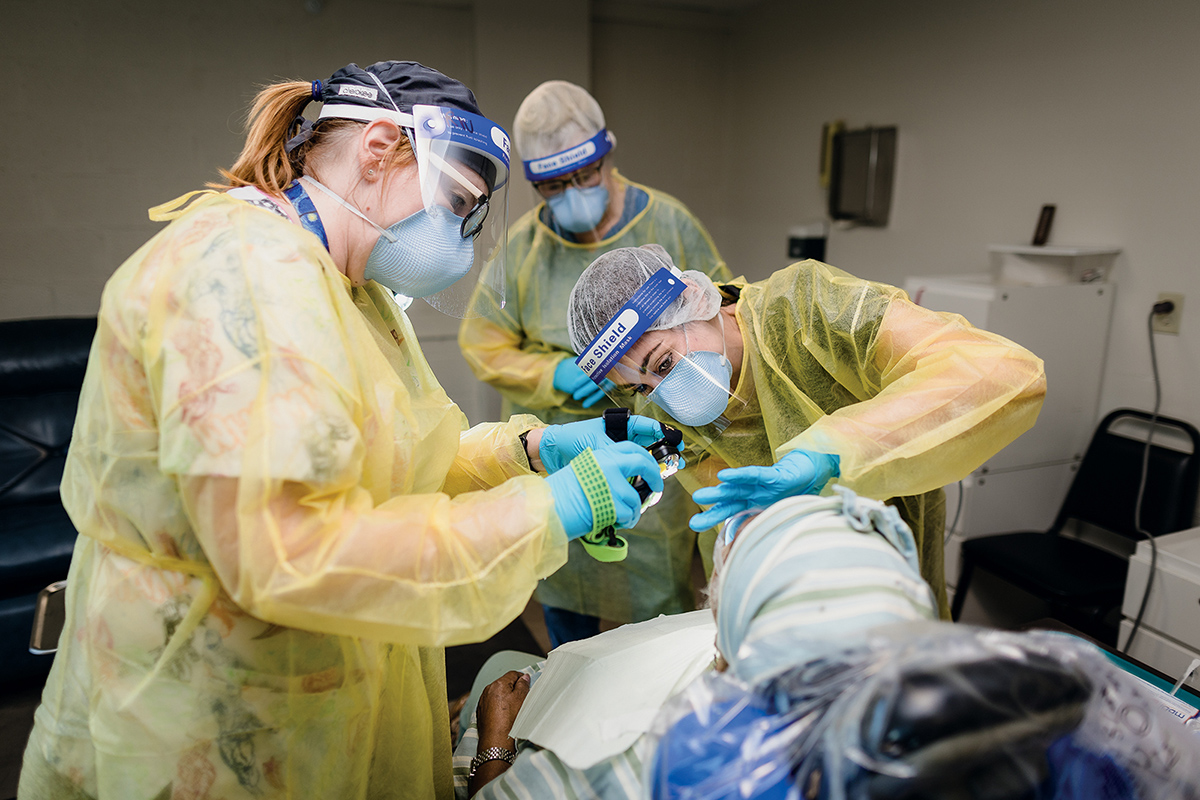 Two dental hygienists examine a patient's teeth.
