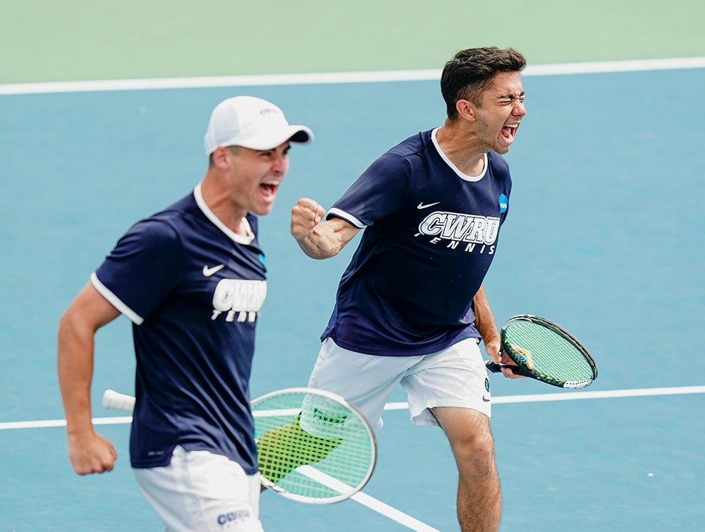 James Hopper and Jonathan Powell on a tennis court celebrating a win.