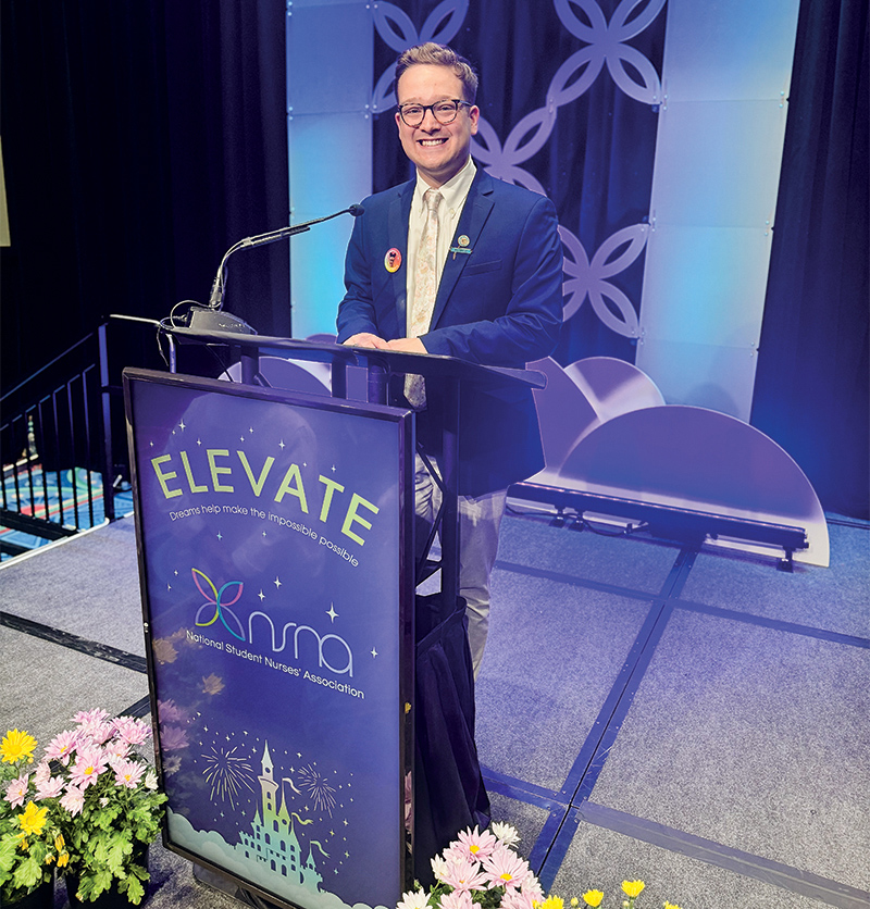 A photo of Ethan Slocum standing at the podium of a meeting of the National Student Nurses Association.