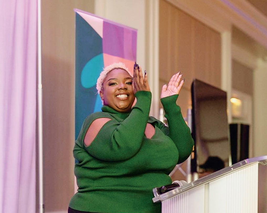 Jazmin Long clapping her hands in celebration at a podium.