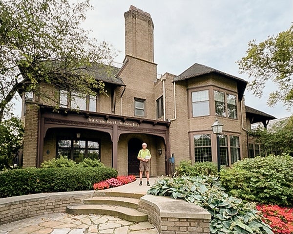 A 2024 photo of an alumnus standing in front of the campus building he lived in as student in the 1970s.