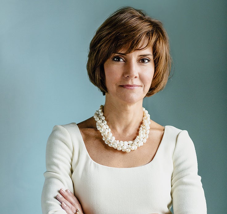 A photo portrait of Capricia Marshall against a blue-gray background and arms crossed.